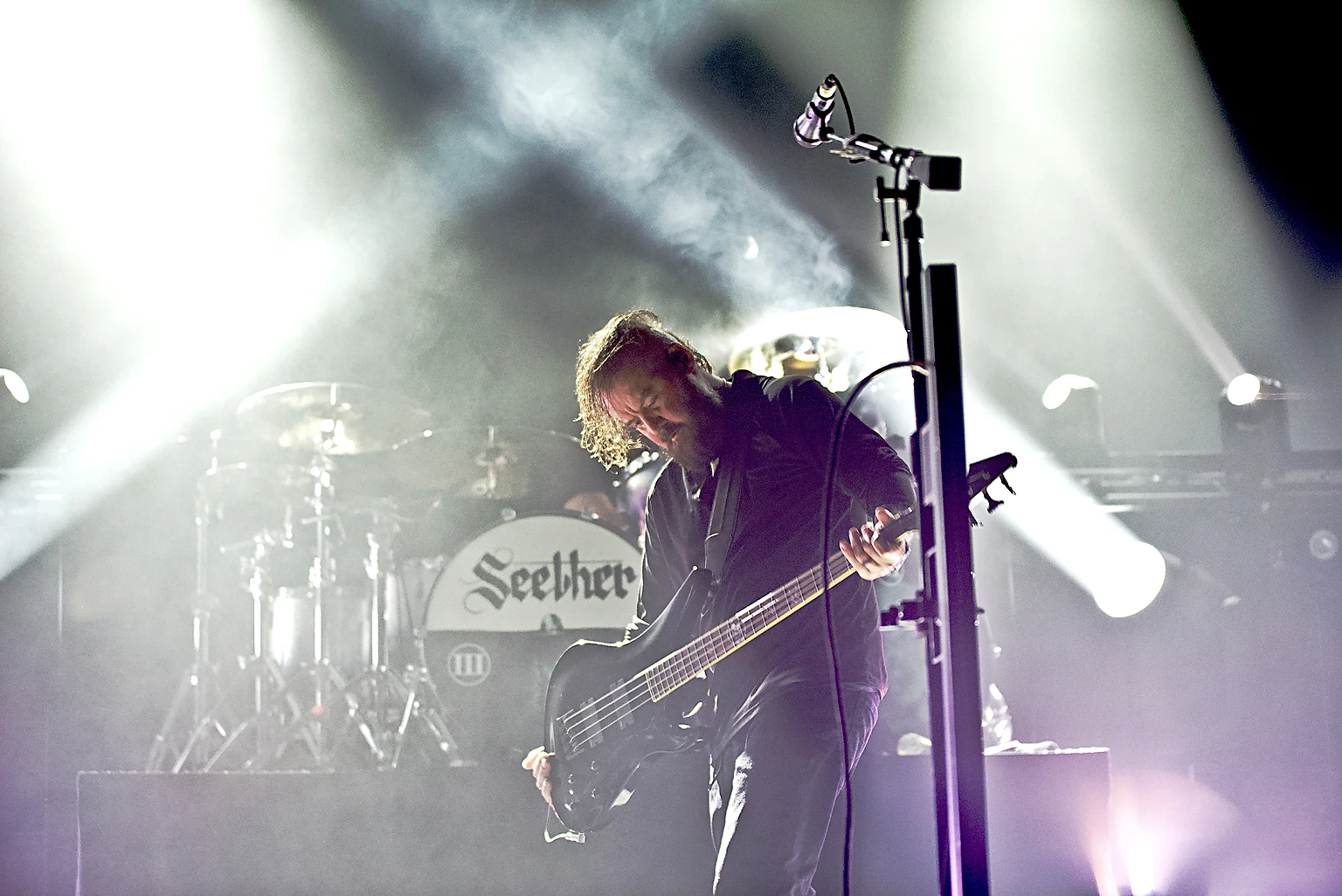 Seether bassist playing in white light beams in front of the Seether drum kit at Toyota Arena, Ontario