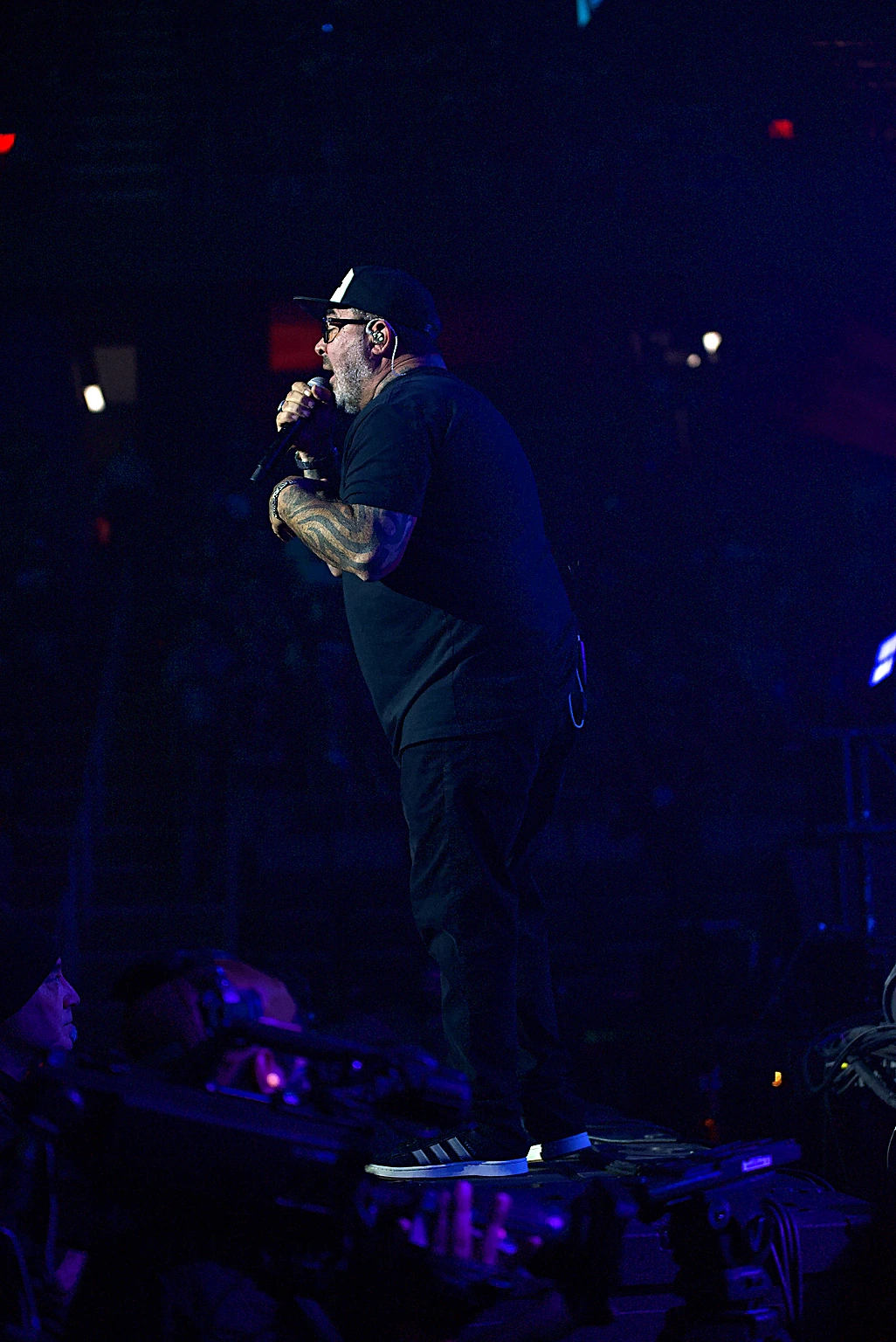 Staind vocalist Aaron Lewis singing alone at the front of the stage in blue light at Toyota Arena, Ontario